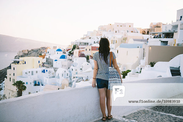 Greece  Santorini  Oia  back view of woman looking to the village at evening twilight