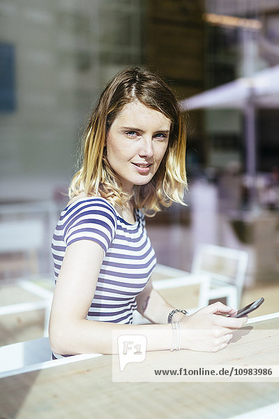 Porträt einer jungen Frau in einem Café mit Blick durchs Fenster