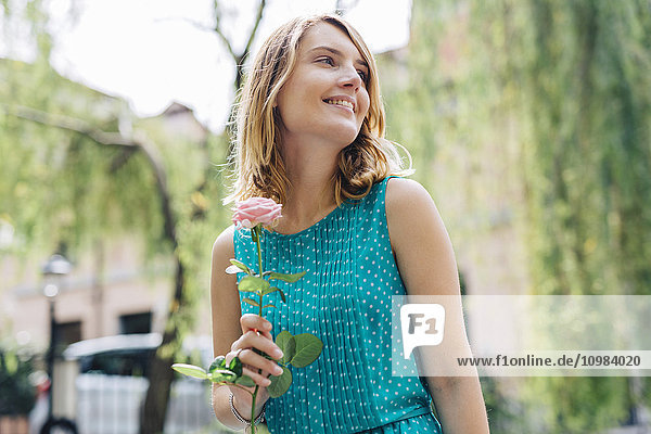 Lächelnde junge Frau mit Rosenblüte