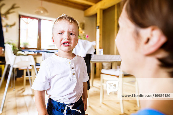 Weinender Junge  der mit seiner Mutter in der Küche steht.