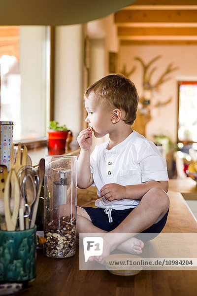 Der kleine Junge spielt in der Küche  knabbert am Essen.