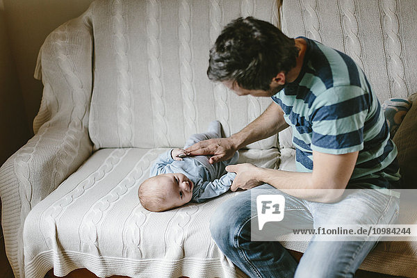 Father with baby boy on couch at home