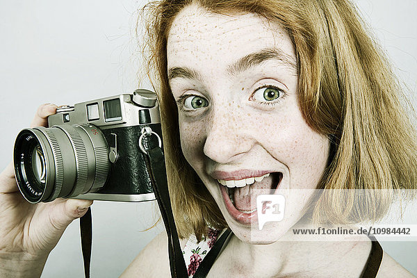 Porträt eines schreienden Mädchens mit einer alten Kamera