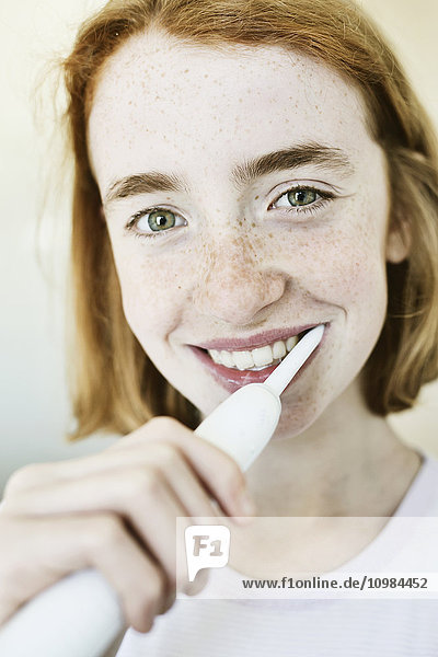 Porträt des lächelnden Mädchens beim Zähneputzen mit elektrischer Zahnbürste