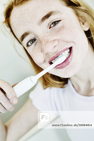 Porträt des lächelnden Mädchens beim Zähneputzen mit elektrischer Zahnbürste