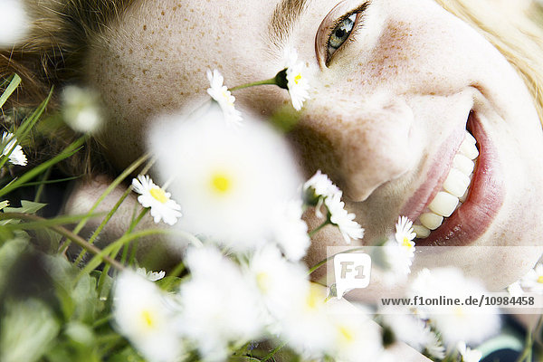 Lächelndes Mädchen auf Blumenfeld liegend  Nahaufnahme