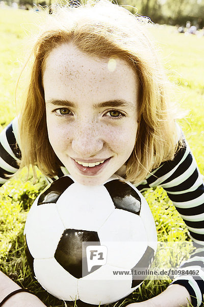 Porträt eines lächelnden Mädchens auf einer Wiese mit Kopf auf Fußball