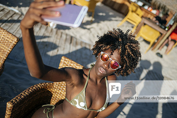 Junge Frau  die einen Selfie mit einem Smartphone in einer Strandbar nimmt