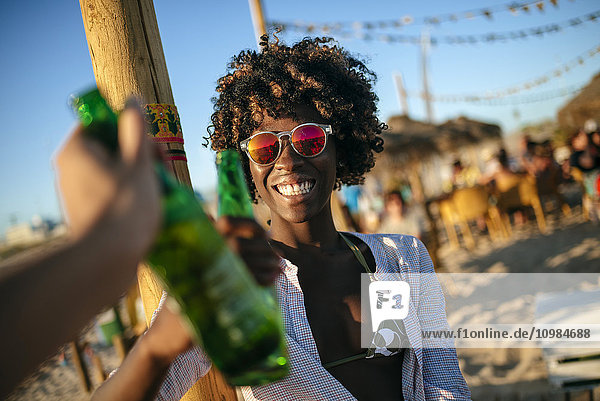 Junge Frau am Strand klirrende Bierflasche