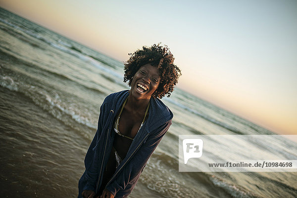 Glückliche junge Frau an der Strandpromenade bei Sonnenuntergang
