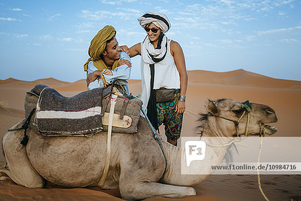 Berbermann mit Frau Tourist mit Kamel in der Wüste