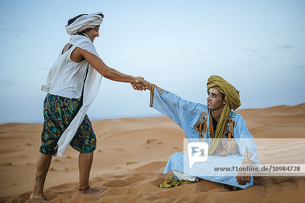 Frau hilft ihrem Berberführer vom Boden aufzustehen