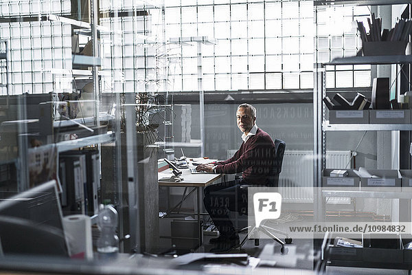 Mature man using laptop at desk in a factory