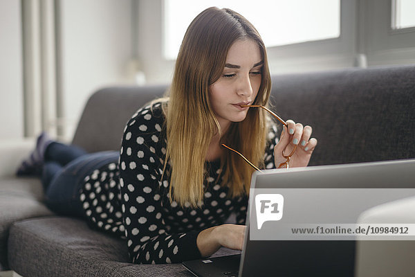 Young woman relaxing on the couch using laptop