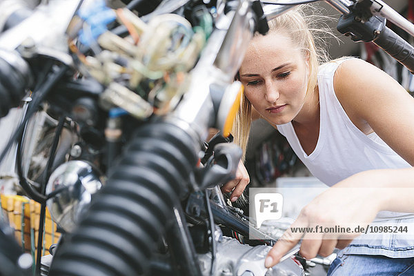 Young woman examining motorbike