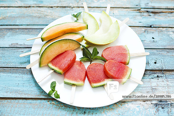 Teller mit hausgemachten Wassermelonen-Eis-Lollies  Scheiben von Galia und Cantaloupe-Melone