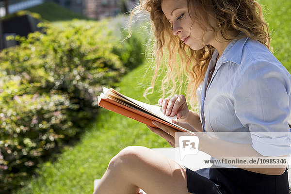 Frau sitzt auf einer Treppe und liest ein Buch.