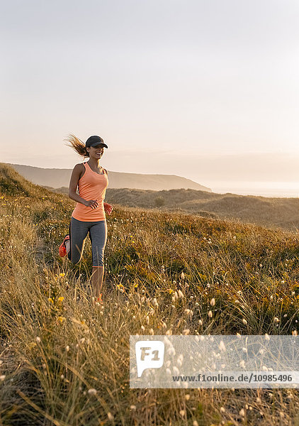 Asturias  Spain  Aviles  young athlete woman running along a coastal path in the evening