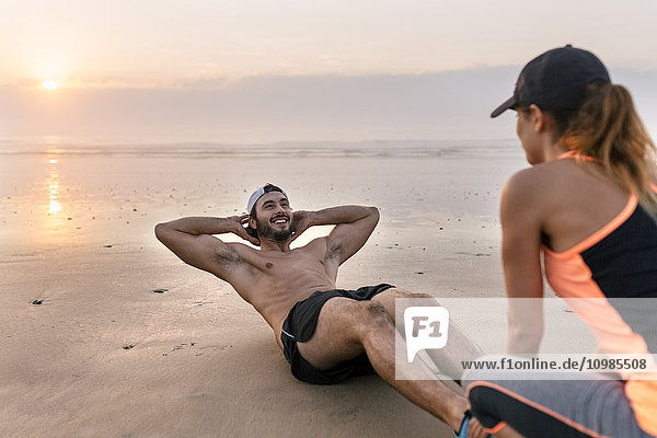 Athletes couple training on the beach at sunset