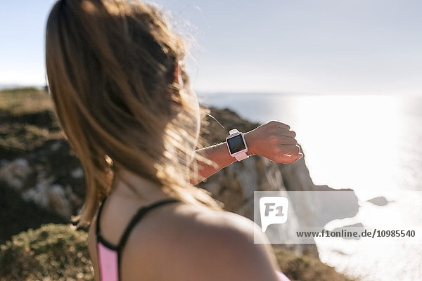 Asturien  Spanien  Asturien  Sportlerin beim Blick auf die Smartwatch  an der Küste