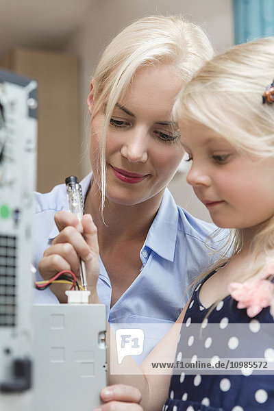 Mutter und kleine Tochter prüfen den Stromfluss des Computers