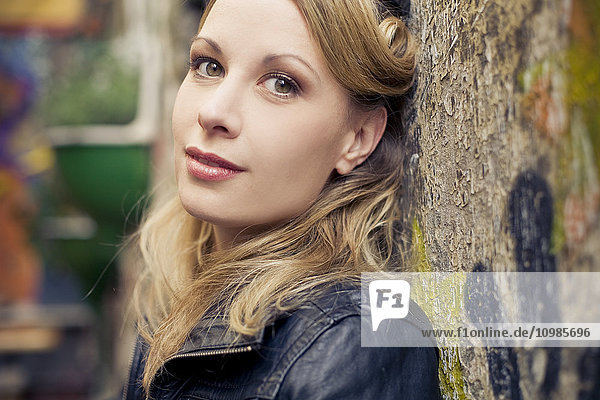 Portrait of blond woman leaning against wall