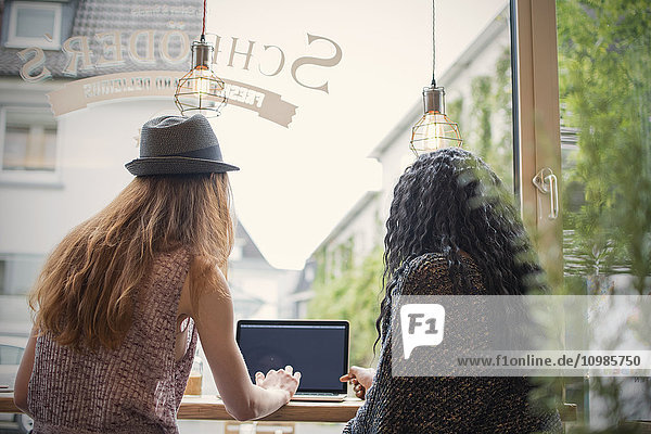 Two young women using laptop in a cafe