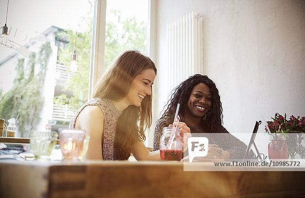 Zwei junge Frauen  die ein digitales Tablett in einem Café benutzen.