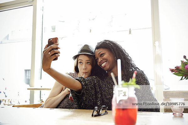 Zwei junge Frauen  die Selfie in einem Cafe nehmen.