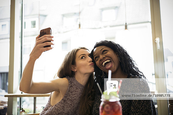 Two young women taking selfie in a cafe