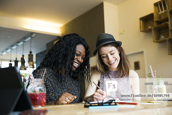 Zwei Freunde mit digitalem Tablett im Cafe