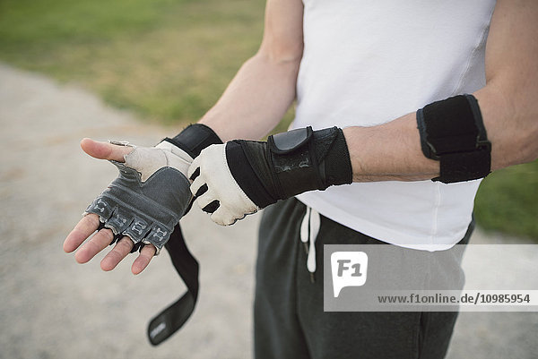 Young man putting on a training glove on the hand to train