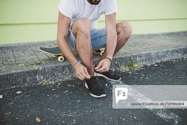 Skateboarder beim Binden seines Schuhs