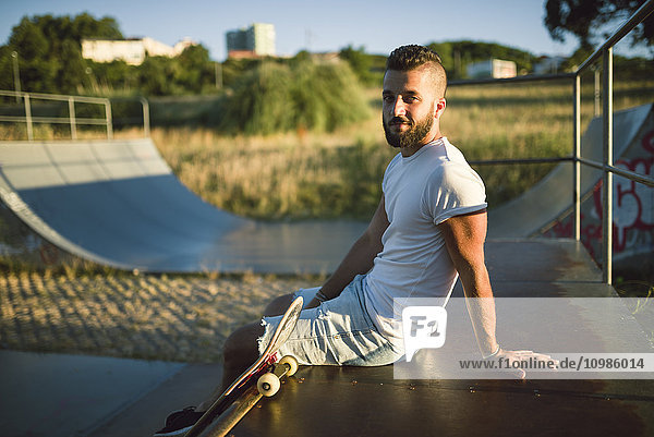 Smiling skateboarder sitting in a skatepark