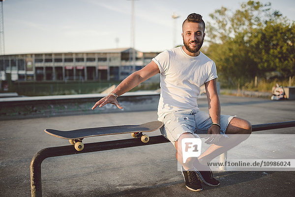 Portrait of skateboarder sitting in a skatepark
