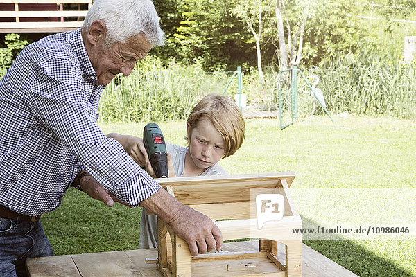 Großvater und Enkel beim Bau eines Vogelhauses
