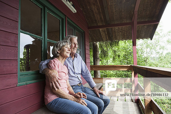 Happy senior couple relaxing on porch of log cabin