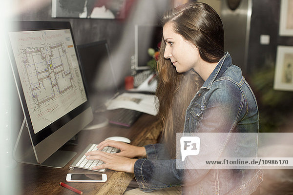 Junge Frau beim Betrachten des Bauplans auf dem Computerbildschirm