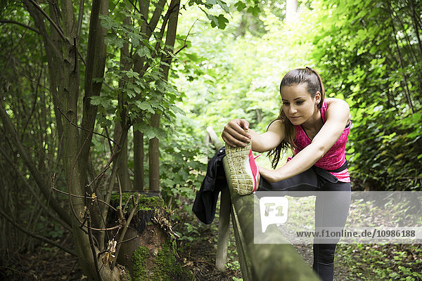 Sportliche junge Frau beim Stretching im Wald