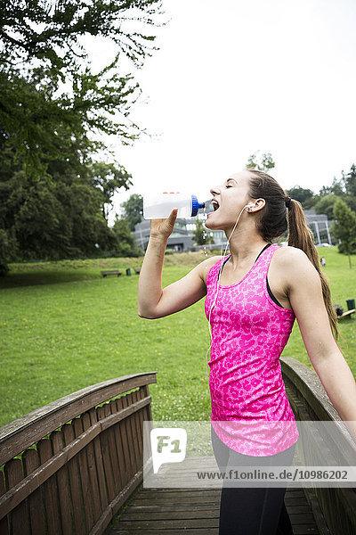 Sportliche junge Frau trinkt aus der Flasche