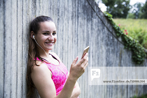 Sportliche junge Frau mit Smartphone und Ohrhörern