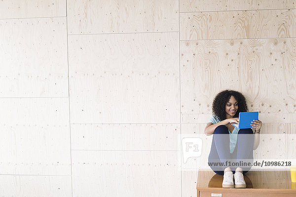 Junge Frau sitzend unter weißem Brett mit Laptop