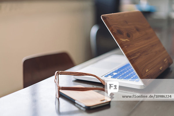 Holz-Laptop  Smartphone und Brille auf dem Schreibtisch