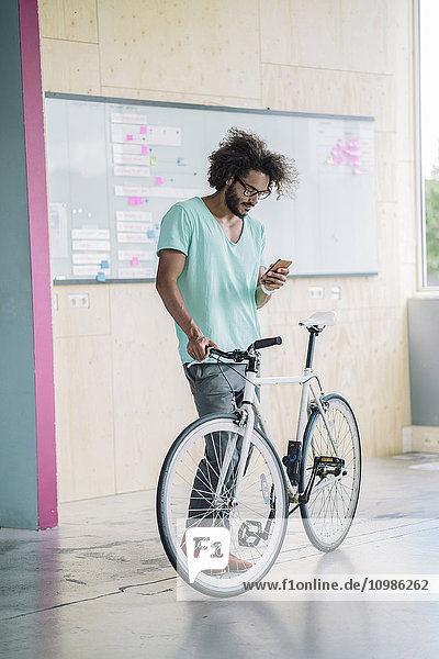 Young man with bicycle using smart phone
