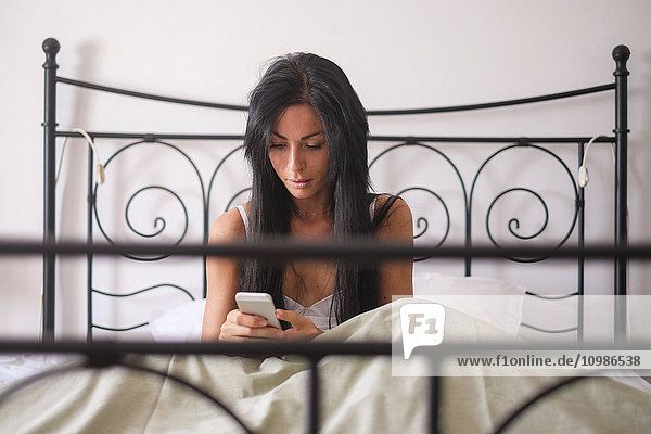 Woman sitting in bed  smartphone