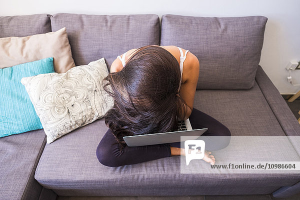 Müde Teenagerin sitzend auf der Couch mit Laptop