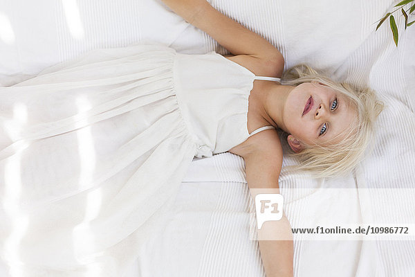 Portrait of little girl lying on a white blanket
