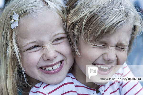 Porträt des lachenden kleinen Jungen und seiner Schwester Kopf an Kopf
