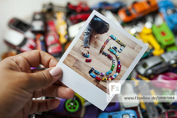 Polaroid of a little kid playing with his cars making a number five