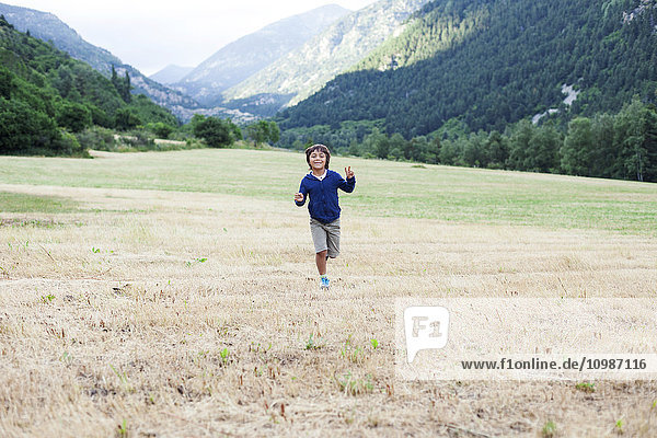 Glücklicher kleiner Junge  der auf einer Bergwiese rennt.
